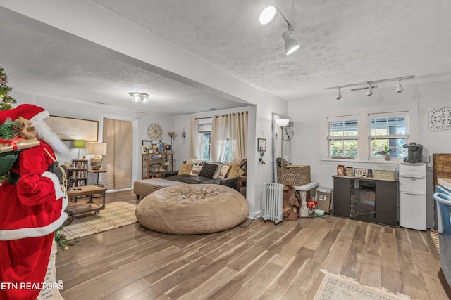 living room featuring hardwood / wood-style floors, rail lighting, a textured ceiling, and radiator heating unit