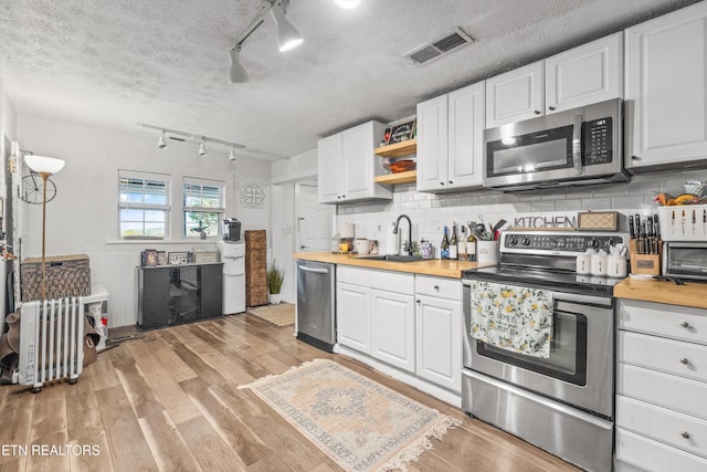 kitchen with white cabinets, sink, butcher block counters, and stainless steel appliances