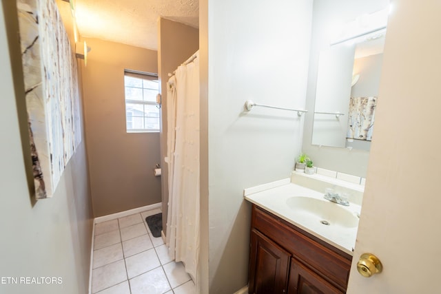 bathroom with tile patterned flooring, vanity, and a textured ceiling