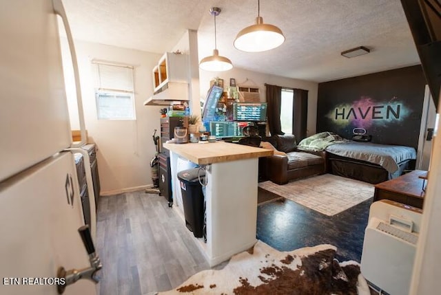 kitchen with pendant lighting, white refrigerator, hardwood / wood-style flooring, a textured ceiling, and butcher block countertops