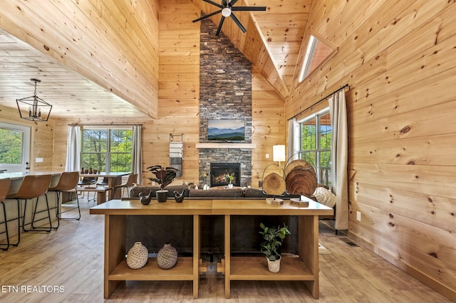 living room with wooden walls, high vaulted ceiling, wooden ceiling, a fireplace, and hardwood / wood-style floors