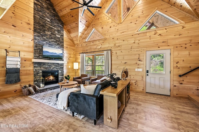 living room with a wealth of natural light, wooden walls, high vaulted ceiling, and wooden ceiling