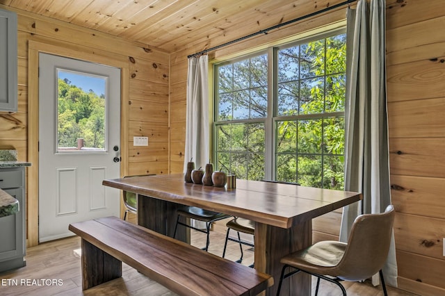 dining space with wood walls, plenty of natural light, light hardwood / wood-style floors, and wooden ceiling