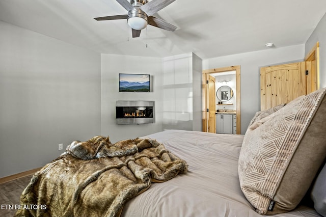 bedroom featuring hardwood / wood-style floors, ensuite bathroom, ceiling fan, and sink