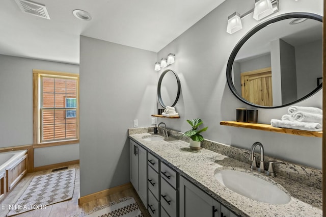 bathroom with a tub to relax in, vanity, and wood-type flooring