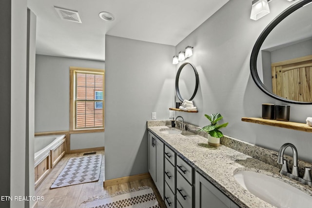 bathroom with hardwood / wood-style floors, vanity, and a bath