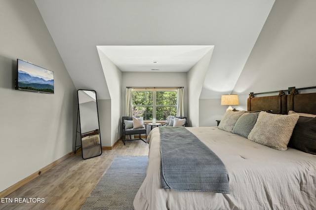 bedroom with light wood-type flooring and vaulted ceiling