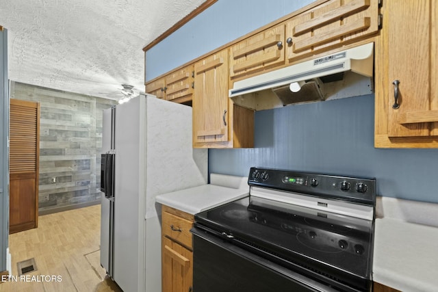 kitchen with light wood-type flooring, a textured ceiling, electric range, and wood walls