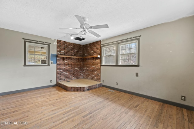 unfurnished room featuring ceiling fan, plenty of natural light, a textured ceiling, and light wood-type flooring