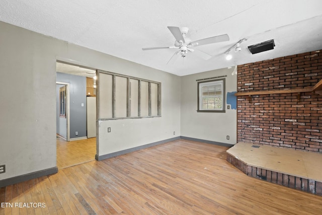 unfurnished living room with ceiling fan, light hardwood / wood-style floors, and a textured ceiling