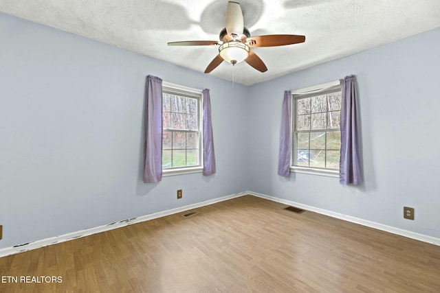 spare room featuring hardwood / wood-style floors, a textured ceiling, and a wealth of natural light