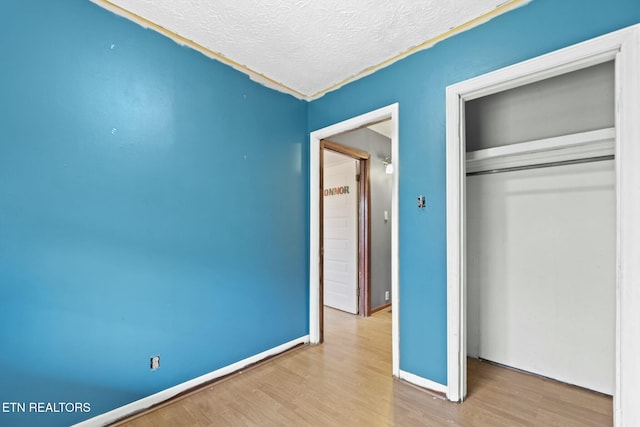 unfurnished bedroom featuring a textured ceiling, hardwood / wood-style flooring, and a closet