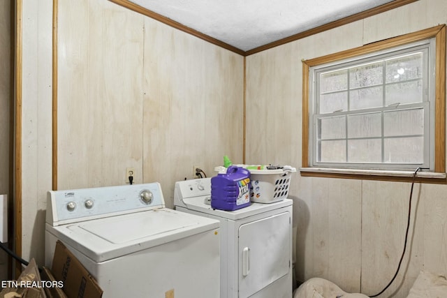 clothes washing area featuring crown molding, washer and clothes dryer, and wood walls