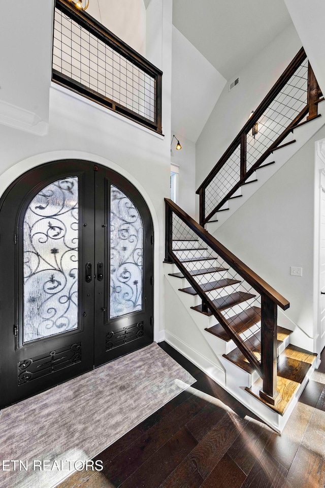 foyer entrance featuring wood-type flooring, high vaulted ceiling, and french doors