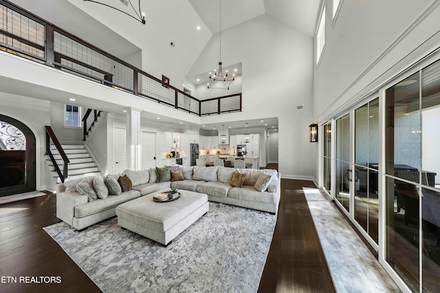 living room with a chandelier, wood-type flooring, high vaulted ceiling, and ornate columns