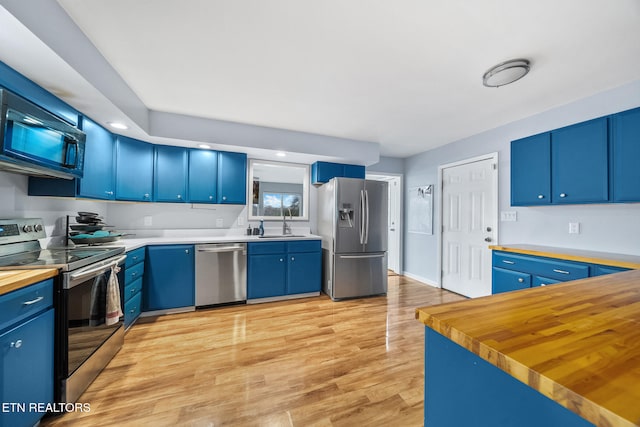 kitchen with wood counters, light wood-type flooring, stainless steel appliances, and blue cabinetry