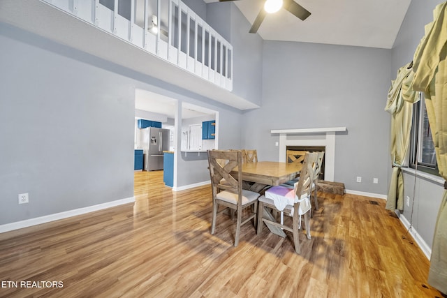 dining room featuring ceiling fan, high vaulted ceiling, and light wood-type flooring