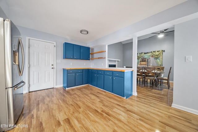 kitchen featuring ceiling fan, stainless steel fridge, light wood-type flooring, and blue cabinets