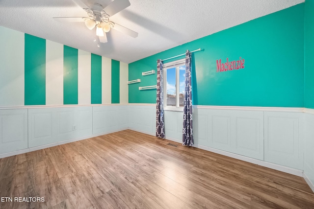 unfurnished room featuring ceiling fan, wood-type flooring, and a textured ceiling