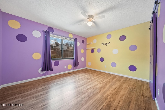 recreation room with a textured ceiling, hardwood / wood-style flooring, and ceiling fan