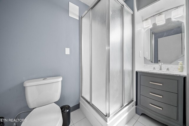 bathroom featuring toilet, vanity, tile patterned floors, and a shower with shower door