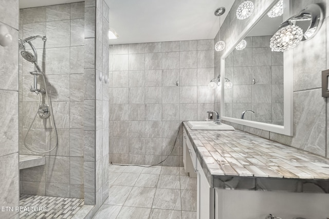 bathroom featuring tiled shower, vanity, tile walls, and tile patterned flooring