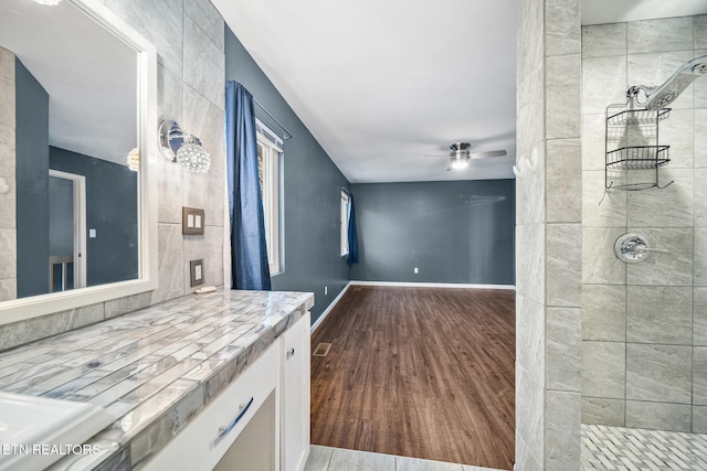 bathroom with a tile shower, ceiling fan, vanity, and hardwood / wood-style flooring