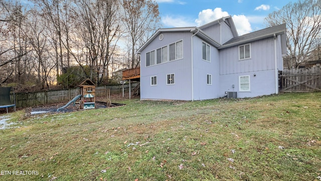 back of property with a playground, a trampoline, and a lawn