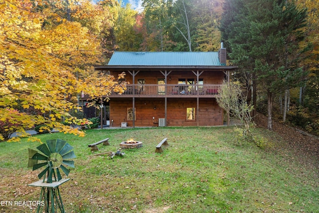 rear view of property featuring a yard, a fire pit, central AC unit, and a deck