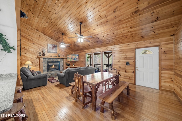 dining room featuring wood walls, light wood-type flooring, and a fireplace