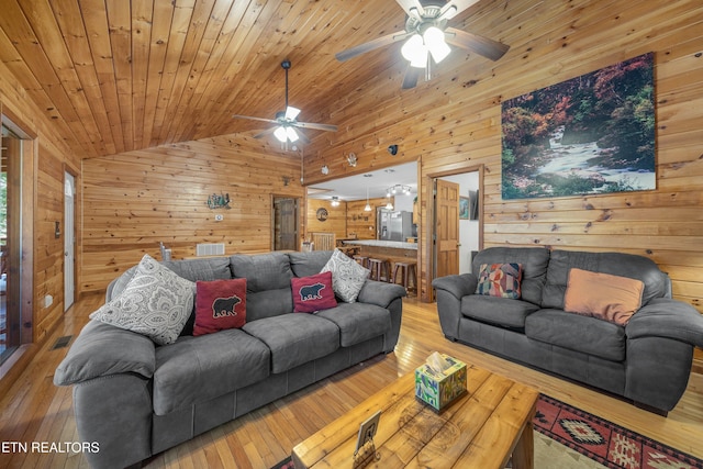 living room featuring ceiling fan, wood-type flooring, and wooden walls