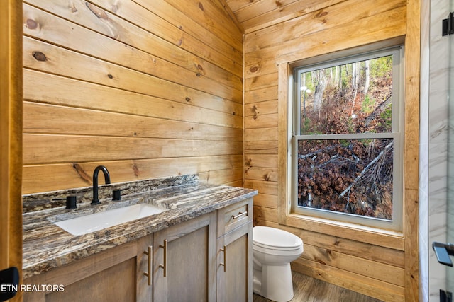 bathroom featuring vanity, toilet, wood-type flooring, and wooden walls