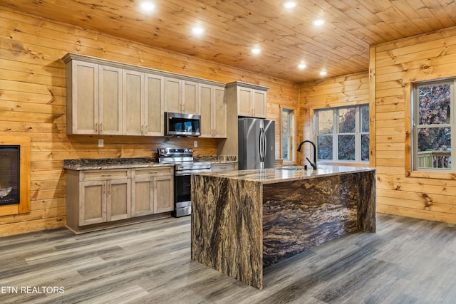 kitchen featuring wooden walls, sink, stainless steel appliances, and hardwood / wood-style flooring