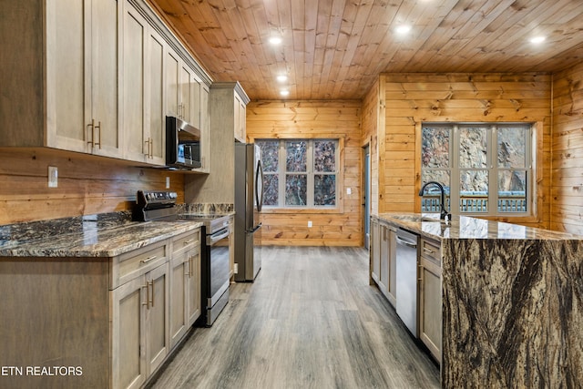 kitchen with stainless steel appliances, wooden walls, and dark stone counters