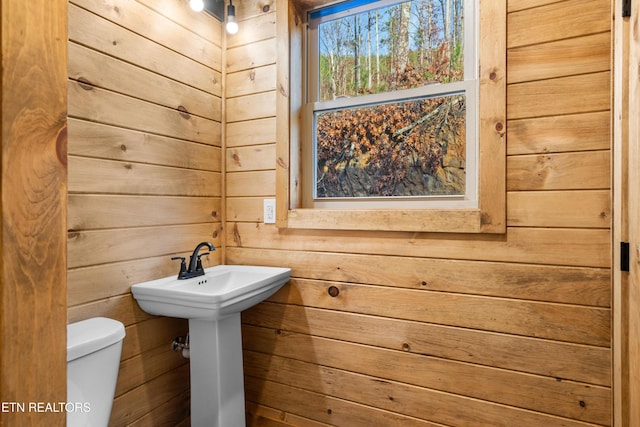 bathroom featuring wood walls and toilet