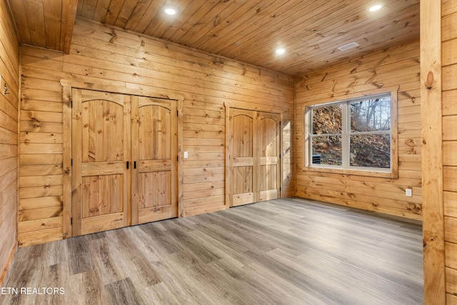 unfurnished bedroom featuring hardwood / wood-style flooring, wood ceiling, and wooden walls