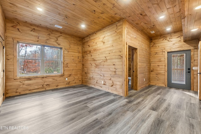 empty room featuring wood ceiling, wooden walls, plenty of natural light, and wood-type flooring