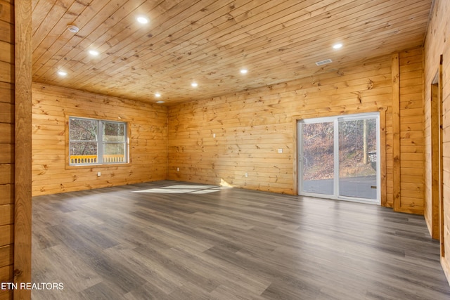 unfurnished room featuring dark hardwood / wood-style floors, wood walls, and plenty of natural light