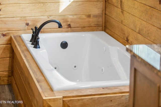 bathroom with a tub and wood walls