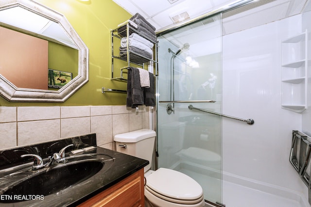 bathroom featuring vanity, a shower with shower door, tile walls, and toilet