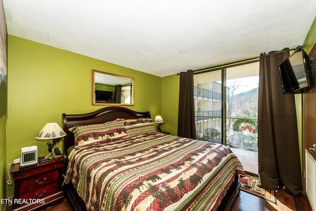 bedroom with a textured ceiling, access to outside, and hardwood / wood-style flooring