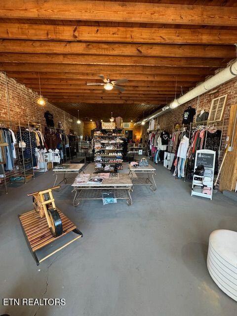 misc room featuring concrete flooring, brick wall, and ceiling fan