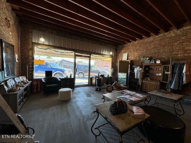 living room featuring brick wall, plenty of natural light, and beam ceiling