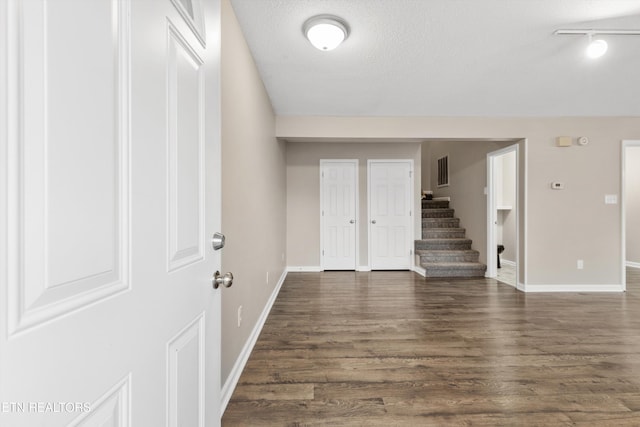 interior space featuring dark hardwood / wood-style flooring, a textured ceiling, and track lighting