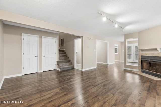 unfurnished living room with dark hardwood / wood-style floors, a textured ceiling, and track lighting