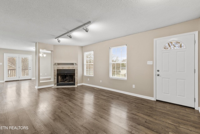 unfurnished living room featuring a textured ceiling, dark hardwood / wood-style flooring, a fireplace, and rail lighting