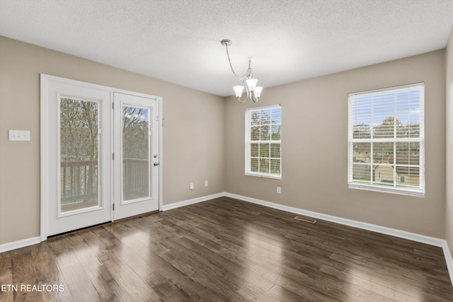 unfurnished room with a textured ceiling, dark hardwood / wood-style floors, and an inviting chandelier