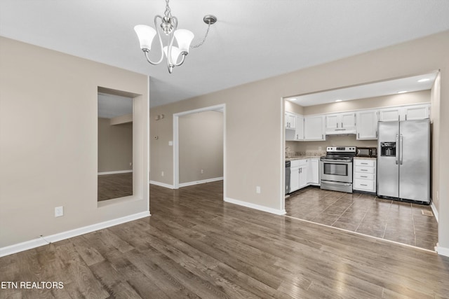 kitchen with dark wood-type flooring, hanging light fixtures, appliances with stainless steel finishes, a notable chandelier, and white cabinetry