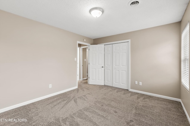 unfurnished bedroom featuring carpet, a textured ceiling, and a closet