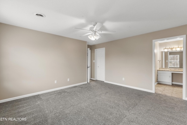 unfurnished bedroom with ensuite bath, ceiling fan, and light colored carpet